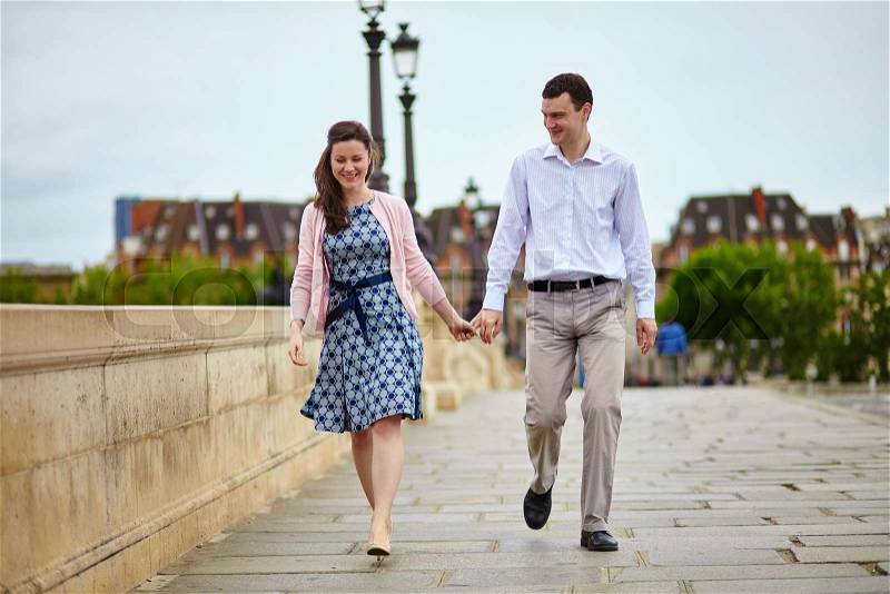 Positive dating couple in Paris walking hand in hand, stock photo