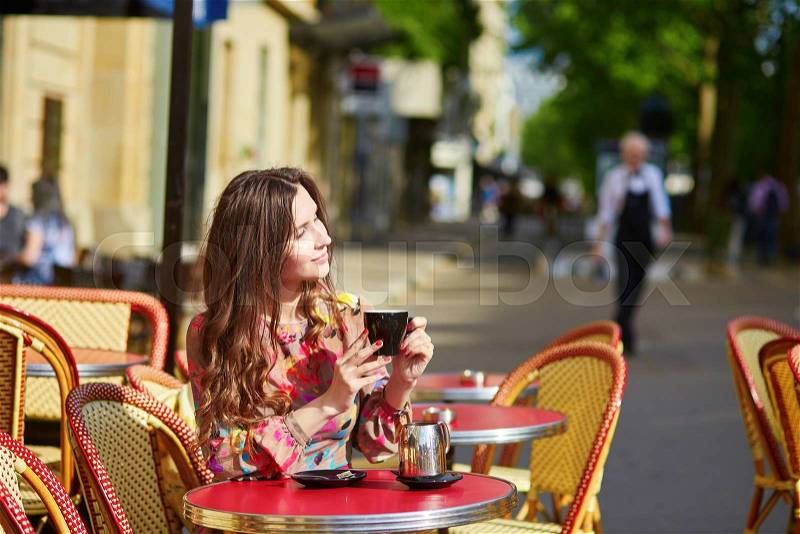 Beautiful young woman in Paris, drinking coffee in an outdoor cafe on a nice sunny day, stock photo