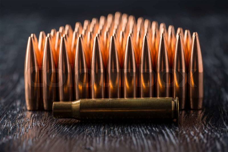 Macro shot of copper bullets that are in many rows to form a triangle on a black wooden background, stock photo