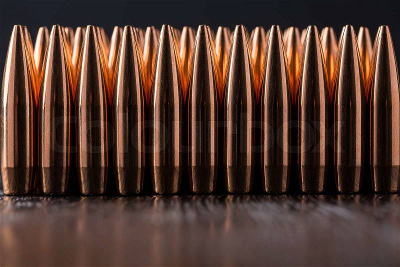 Macro shot of copper bullets that are in many row on a black wooden background, stock photo