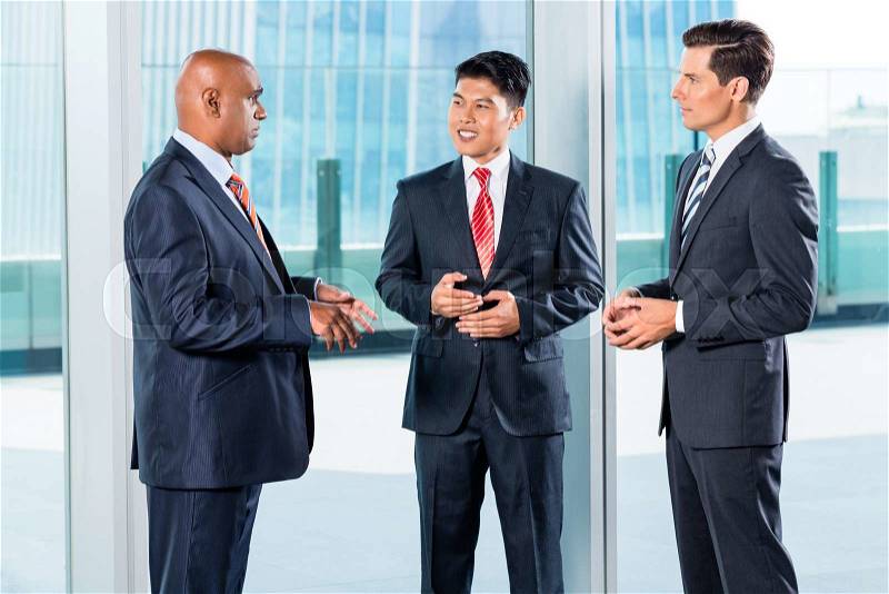 Multi ethnic business team reporting to Indian CEO discussing in front of city skyline, stock photo