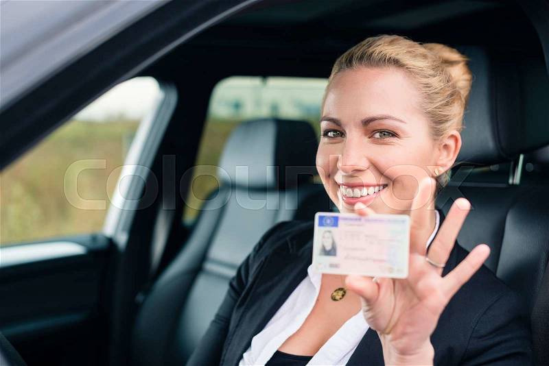 Woman showing her driving license out of car window, stock photo