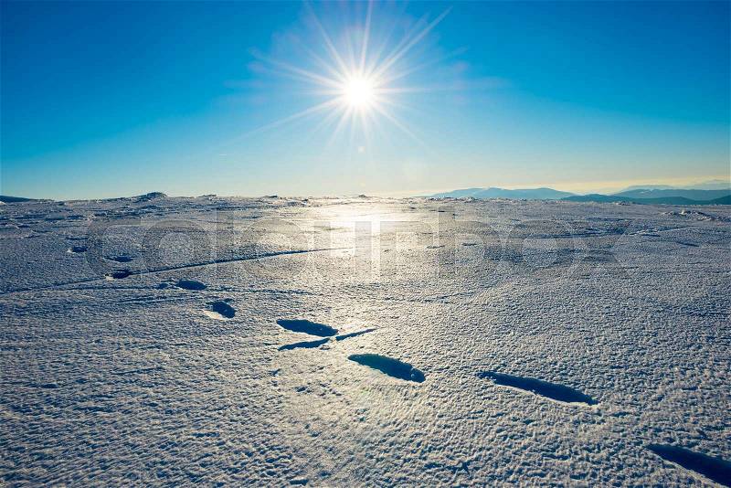 Footprints on the snow. Bright landscape with sun in winter mountains, stock photo