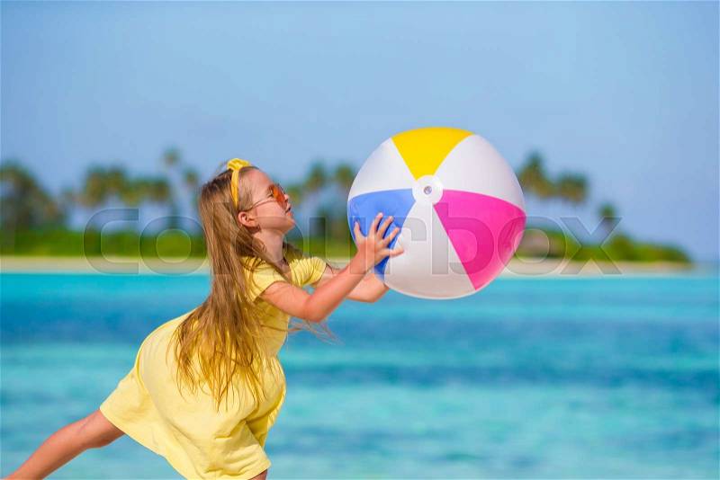 Little adorable girl playing with air ball outdoor on beach, stock photo