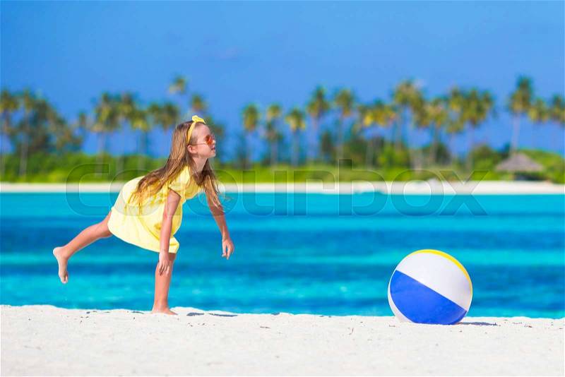 Little adorable girl playing with air ball outdoor on beach, stock photo