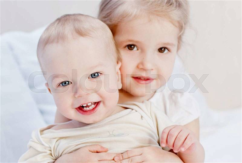 Happy little sister hugging her brother on a white background, stock photo