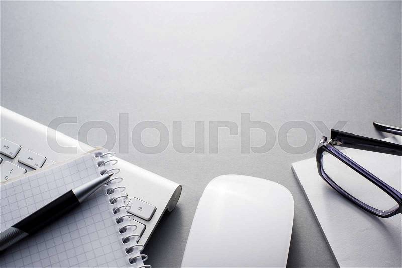 High Angle View of Mac Computer Keyboard and Mouse on Grey Desk with Note Book, Eyeglasses and Pen and Ample Copy Space, stock photo