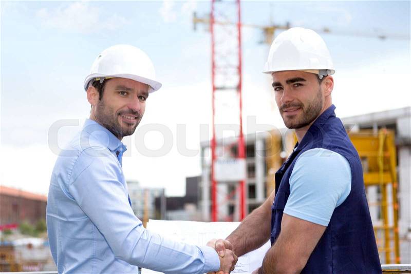 View of an architect and worker handshaking on construction site , stock photo