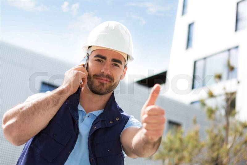 View of a Yong attractive worker using mobile phone on a construction site , stock photo