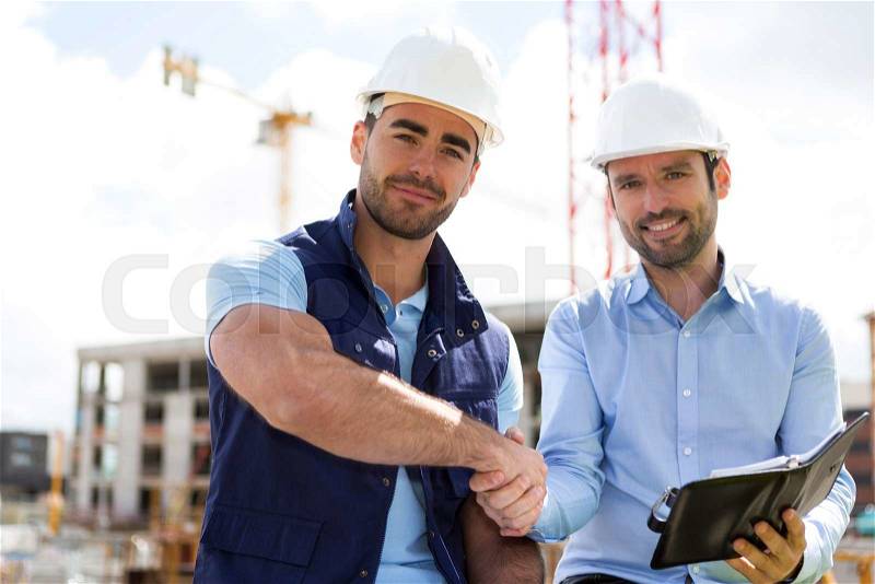 View of an architect and worker handshaking on construction site , stock photo