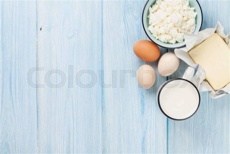 Dairy products on wooden table. Milk, cheese, egg, curd cheese and butter. Top view with copy space, stock photo