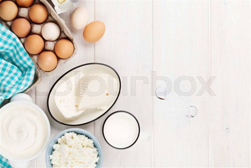 Dairy products on wooden table. Sour cream, milk, cheese, eggs, yogurt and butter. Top view with copy space, stock photo