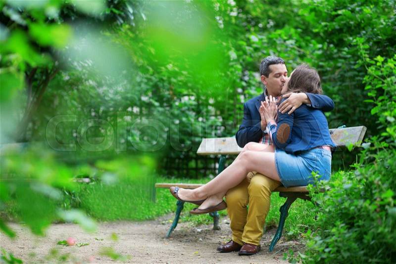 Young loving couple kissing on a bench, stock photo