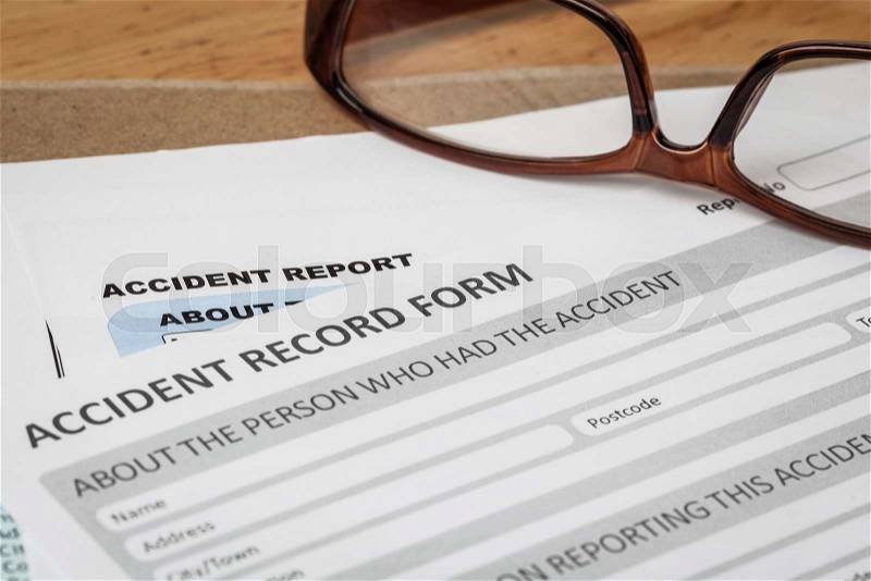 Accident report application form on brown envelope and eyeglass, business insurance and risk concept; document is mock-up, stock photo