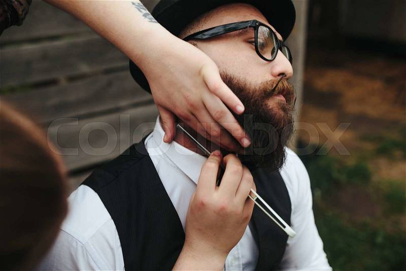 Barber shaves a bearded man in vintage atmosphere, stock photo