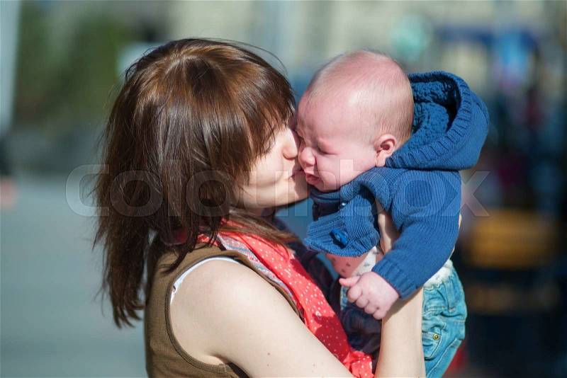 Young mother calming her crying baby boy, stock photo