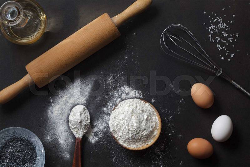 Flour and ingredients on black table. Top view, stock photo