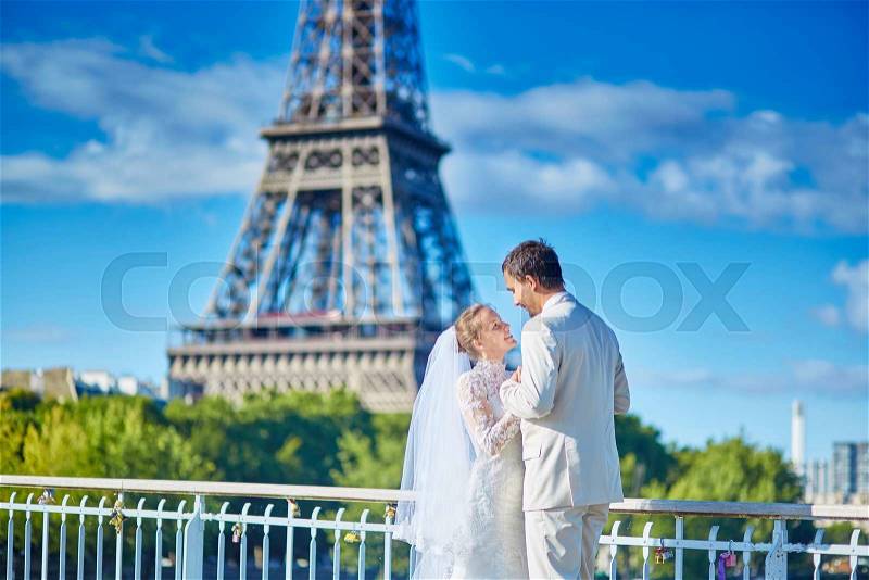 Beautiful just married couple in Paris near the Eiffel tower in Paris, stock photo