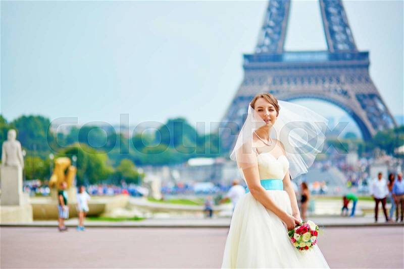 Happy young beautiful bride holding wedding bouquet. photo taken in Paris, near the Eiffel tower, stock photo