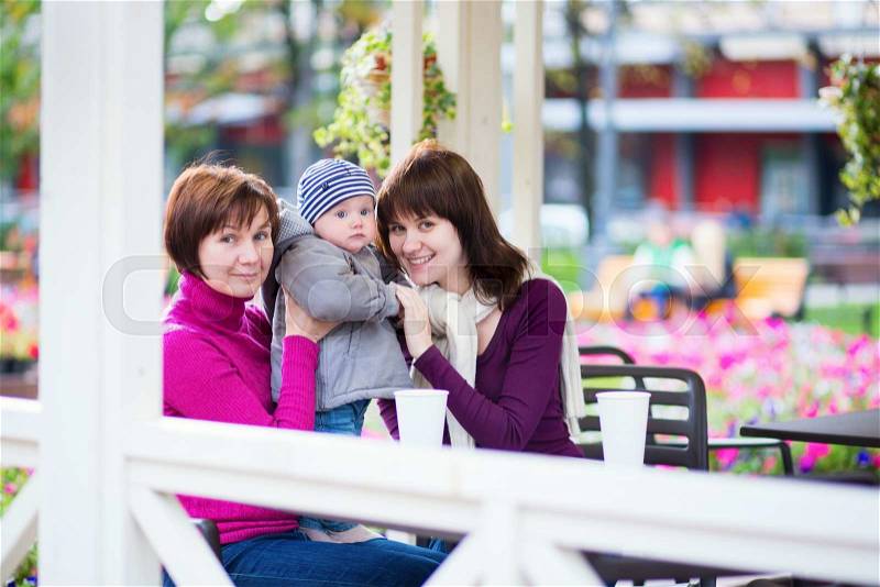 Three generations family - grandmother, mother and little son spending time together in an outdoor cafe, stock photo