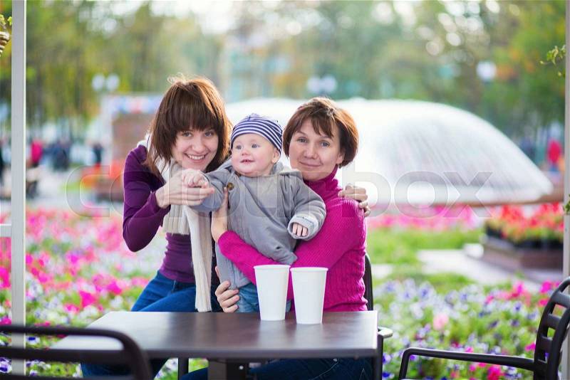 Three generations family - grandmother, mother and little son spending time together in an outdoor cafe, stock photo