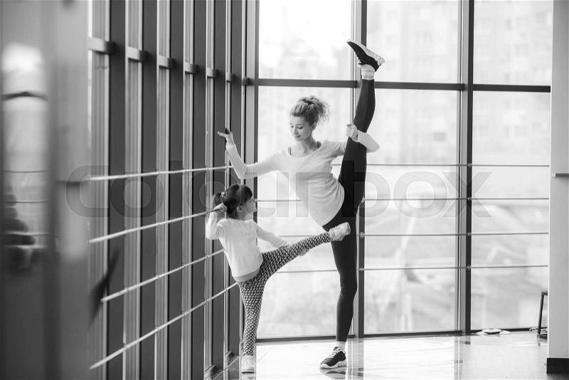 Mother learning daughter to make a high leg strech, stock photo