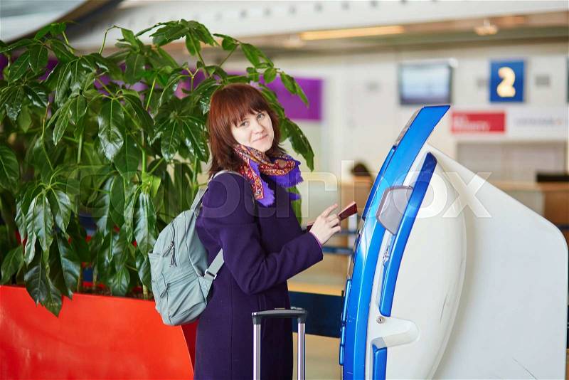 Young female passenger at the airport, doing self check-in, stock photo