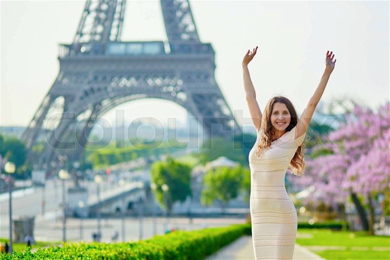 Beautiful young woman in Paris, near the Eiffel tower on a nice and sunny spring day, stock photo
