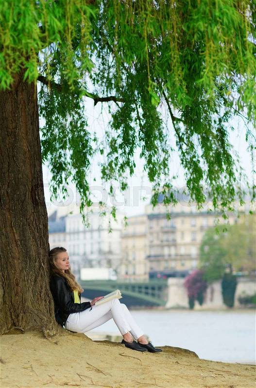 Girl reading under a tree in Paris, stock photo