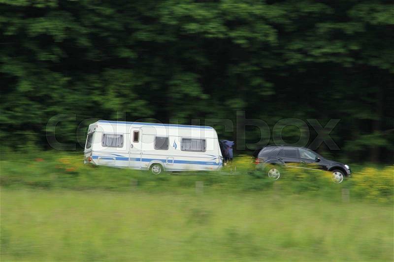 The tourists with the caravan behind the car going on holiday in spring, stock photo