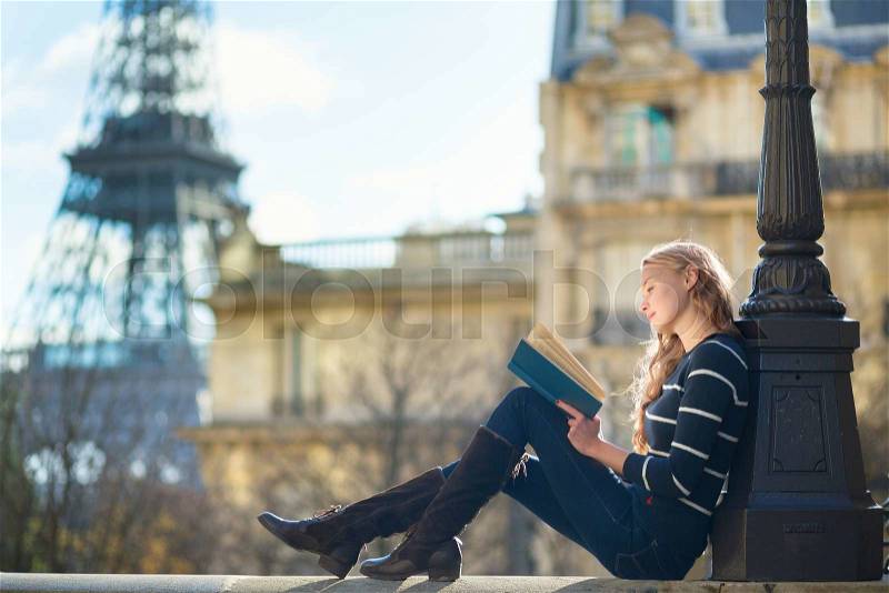 Beautiful young woman in Paris, reading a book, stock photo