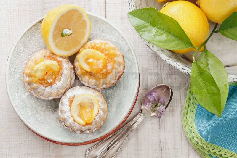 Mini lemon bundt cakes. Mini lemon bundt cakes dusted with icing sugar and fresh lemons over rustic wooden background. Macro, selective focus. Natural light, stock photo