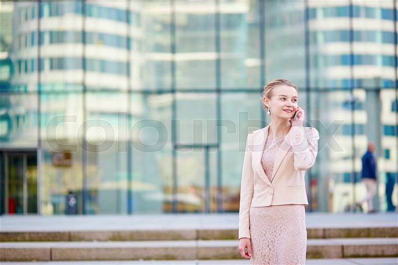 Young confident business woman in modern glass office interior using the mobile phone, stock photo
