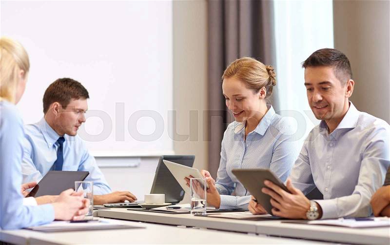 Business, people and technology concept - smiling business team with tablet pc computer meeting in office, stock photo