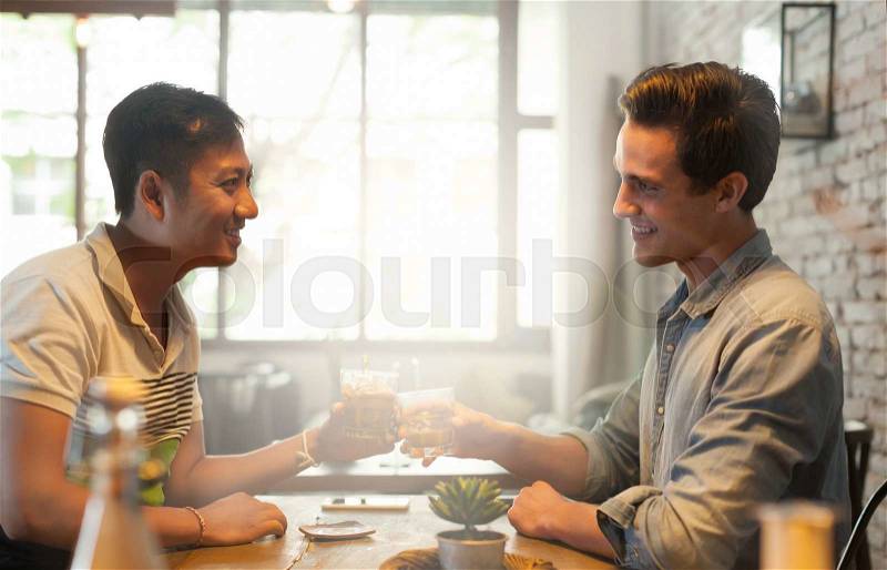 Two Men Cheers Toast Drink, Asian Mix Race Friends Guys Happy Smile Sitting at Cafe Natural Light, stock photo