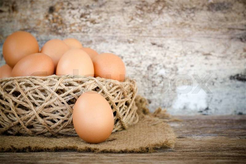 Chicken egg in nest on wood background, stock photo