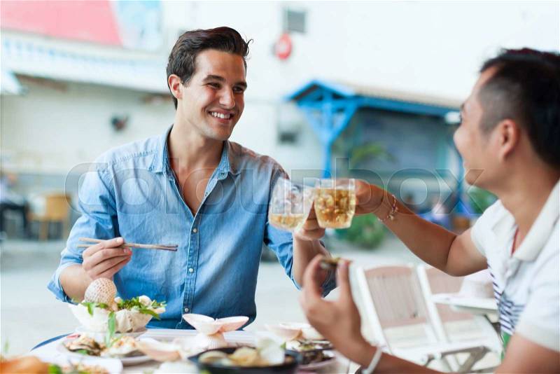 Tourist Men Cheers Toast Drink, Asian Mix Race Friends Guys Happy Smile Sitting at Cafe Eating Asian Food Street Local Cafe, stock photo