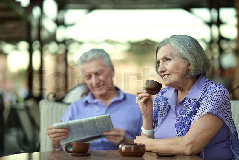 Senior couple drinking coffee outside at the resort during vacation, stock photo