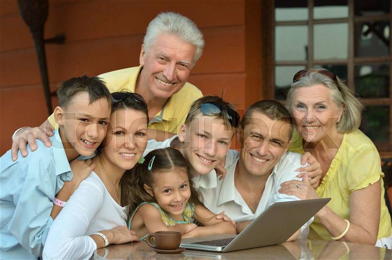 Happy family sitting with laptop on table, stock photo