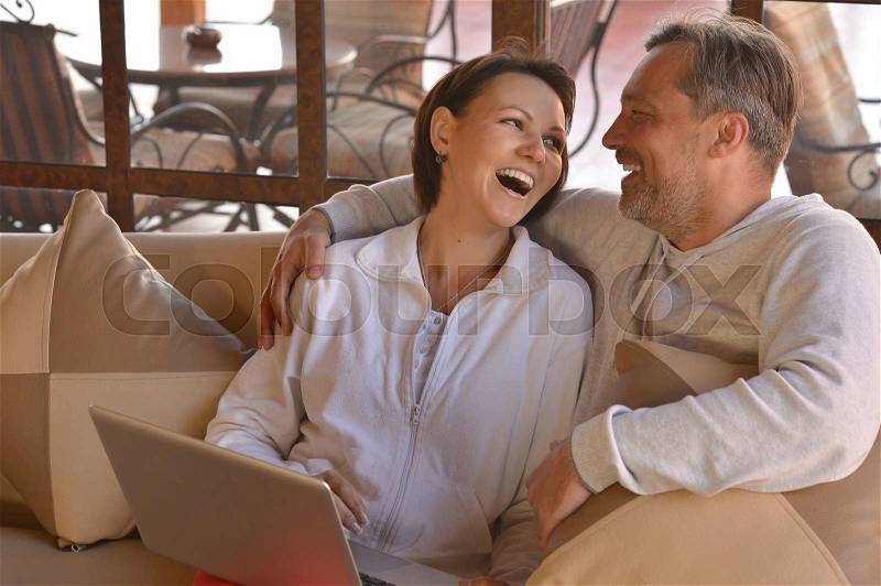 Happy couple with laptop at the table, stock photo