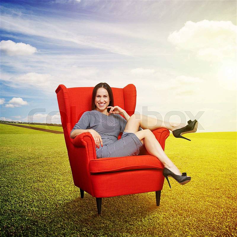 Smiley young woman resting on red chair at outdoors, stock photo