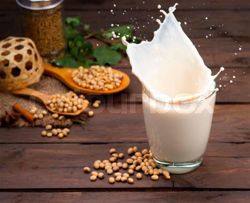 Soy milk splash with beans on wood, stock photo