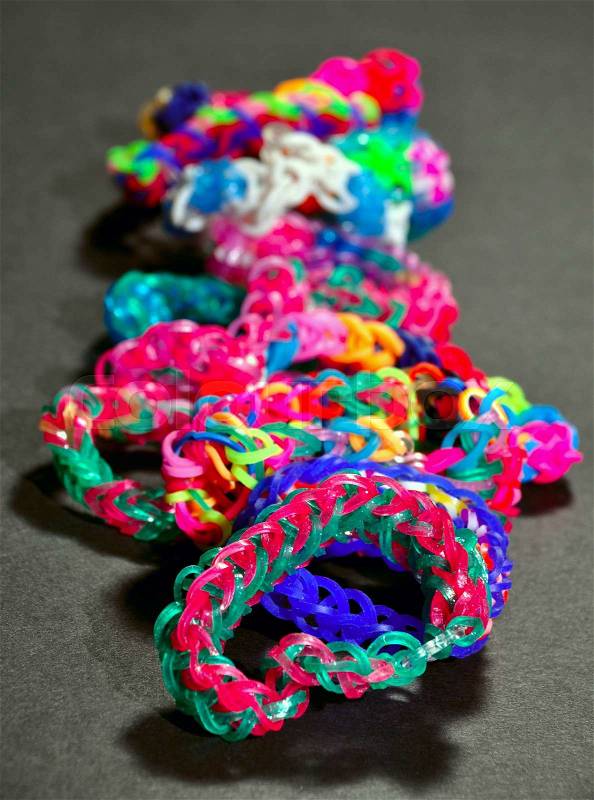 Colorful background rainbow colors rubber bands loom bracelets on black background. Trendy kids\' fashion accessories, stock photo