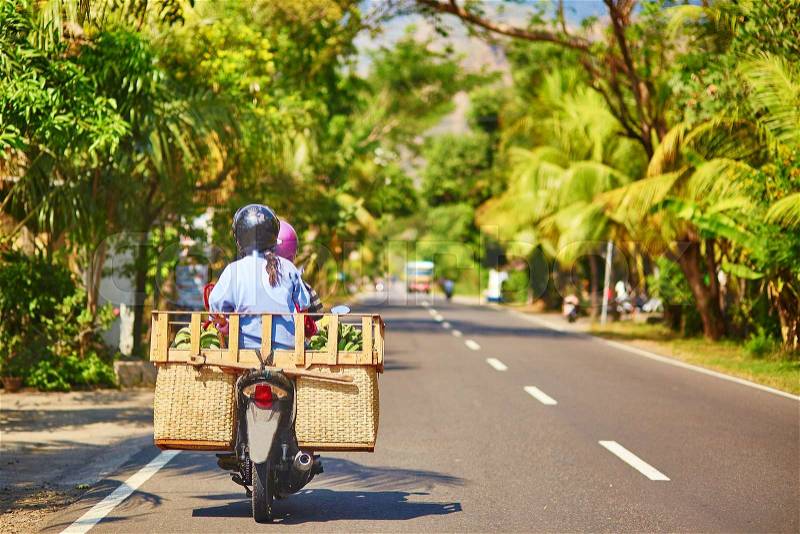 Balinese man with huge luggage on scooter, stock photo