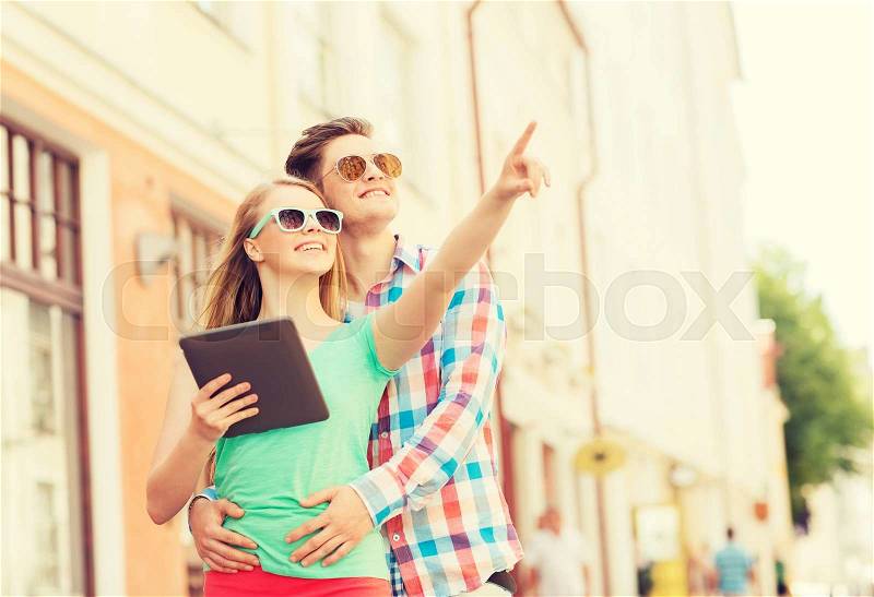 Travel, vacation, technology and friendship concept - smiling couple with tablet pc computer in city, stock photo