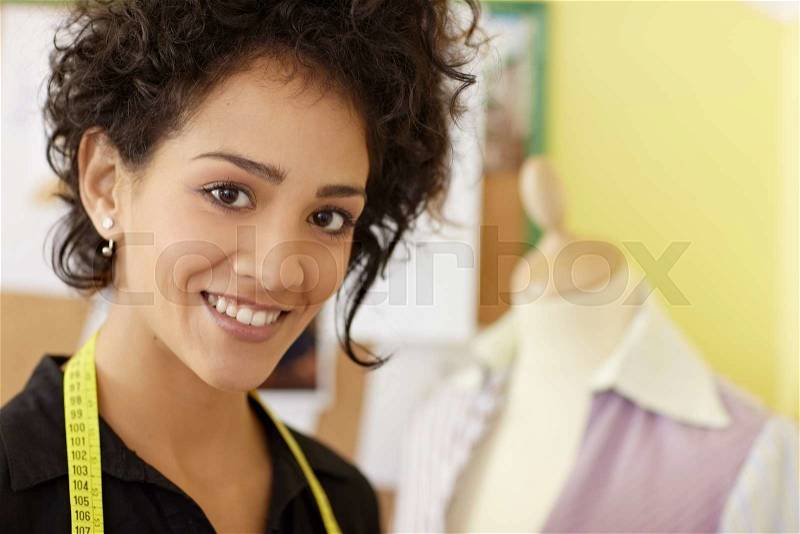 Portrait of young hispanic female dressmaker with mannequin in background. Horizontal shape, head and shoulders, copy space, stock photo