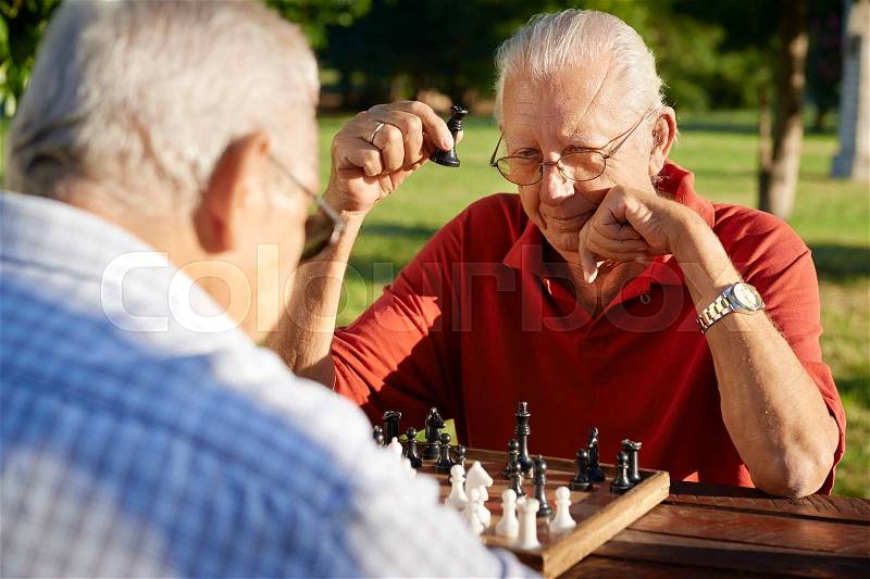 Active retired people, old friends and free time, two senior men having fun and playing chess at park. Head and shoulders, stock photo