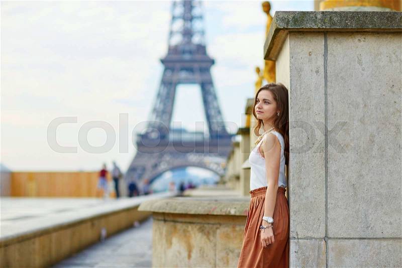 Beautiful young Parisian woman in long skirt near the Eiffel tower on a summer day, stock photo
