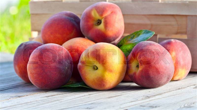 Juicy peaches on wooden table in garden, stock photo
