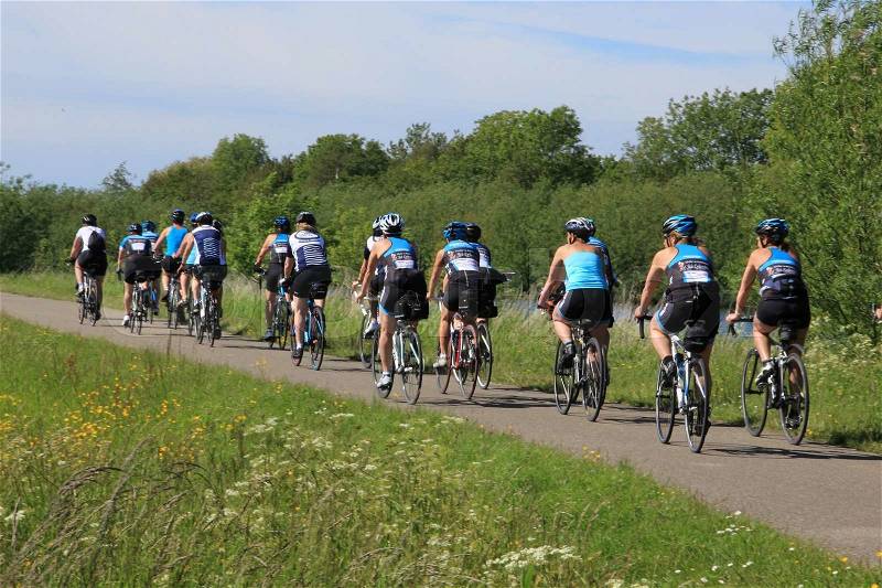 The group of cyclers cycling over the bike path in the park in spring, stock photo